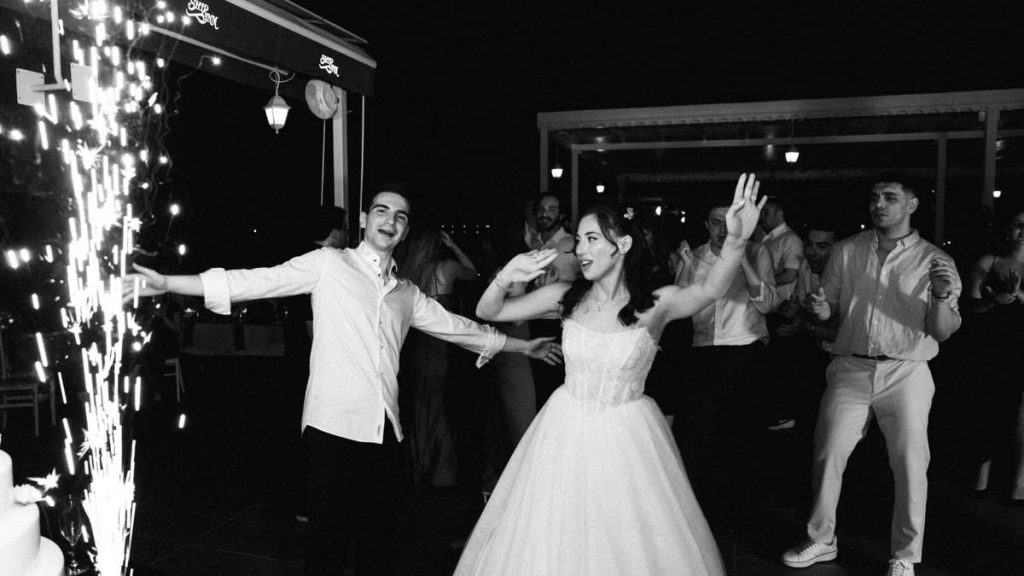 Joyful wedding celebration in Antalya with a dancing couple and fireworks.