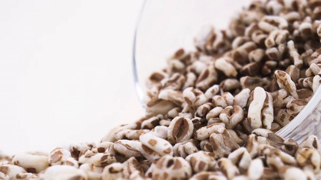High-resolution close-up of puffed cereal grains spilling from a glass bowl, perfect for healthy food concepts.